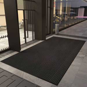 Close-up of heavy-duty entrance mat in busy commercial building foyer