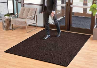 Top-view of a stylish coir entrance mat at a UK home doorway, trapping mud and moisture from shoes